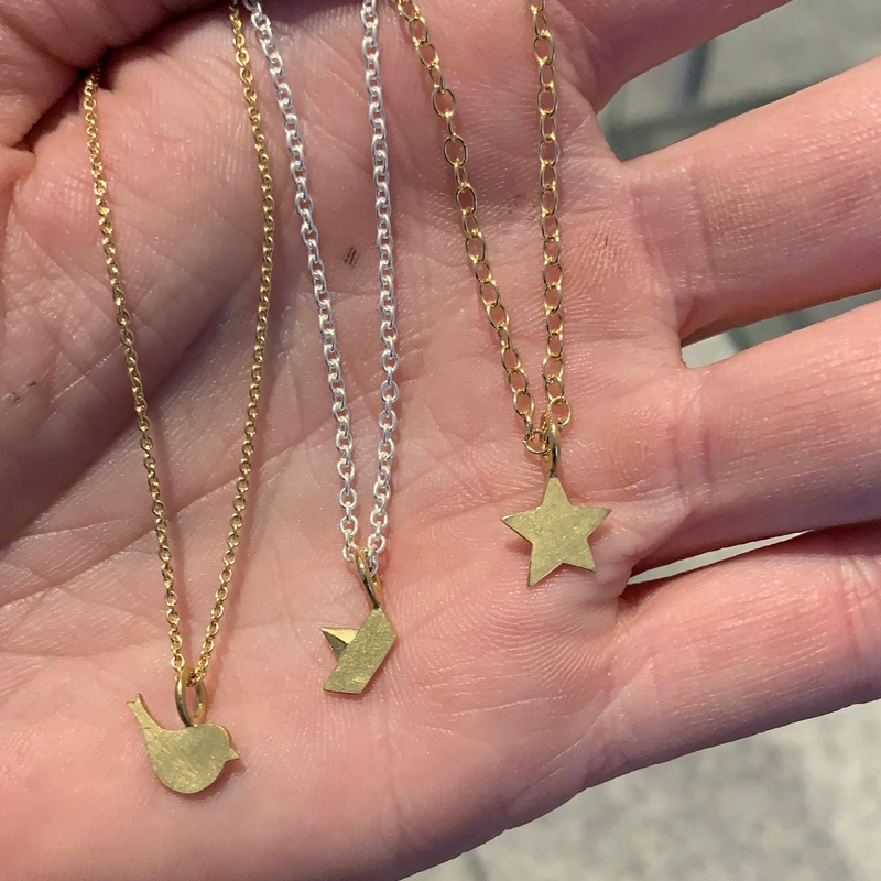 zarte Gold und Silberketten mit kleinen Goldanhängern liegen auf einer Handfläche
