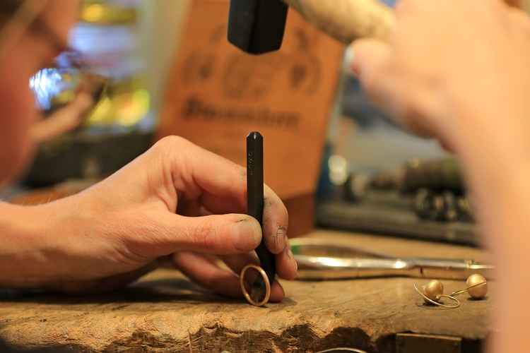 Ein Ring wird mit Hilfe von Hammer und Meißel in Form geklopft.