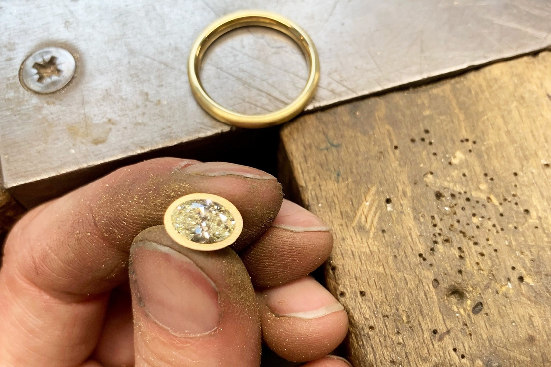 Ein Frisch geschliffener Goldring, an der Hand sind kleine, funkelnde Goldraspeln zu erekennen.