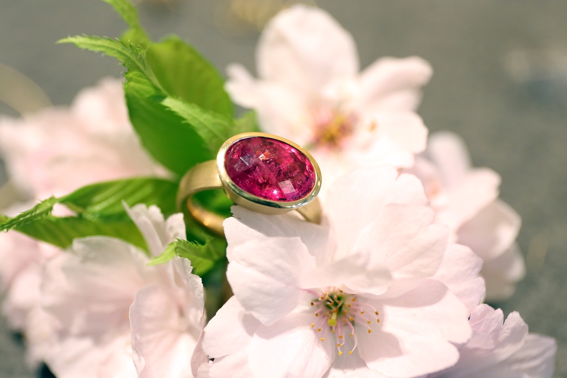 Ein Ring mit rosa Edelstein auf rosa Kirschblüten.